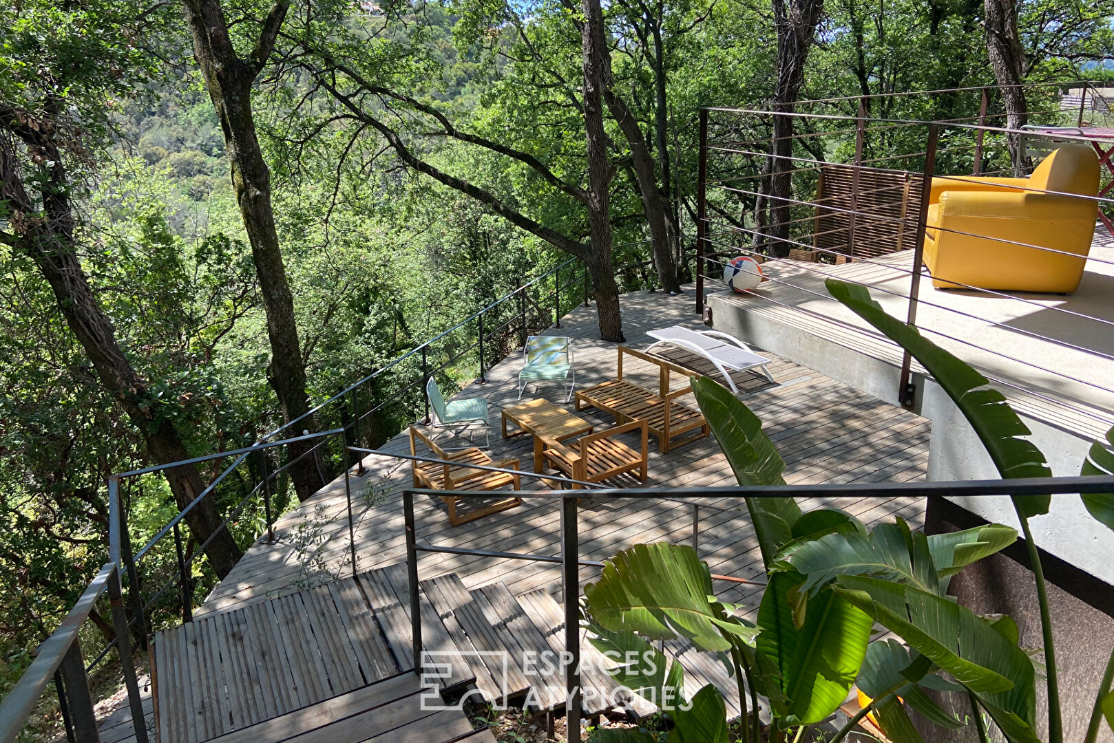 Maison brutaliste avec terrasse en bois au milieu de la forêt