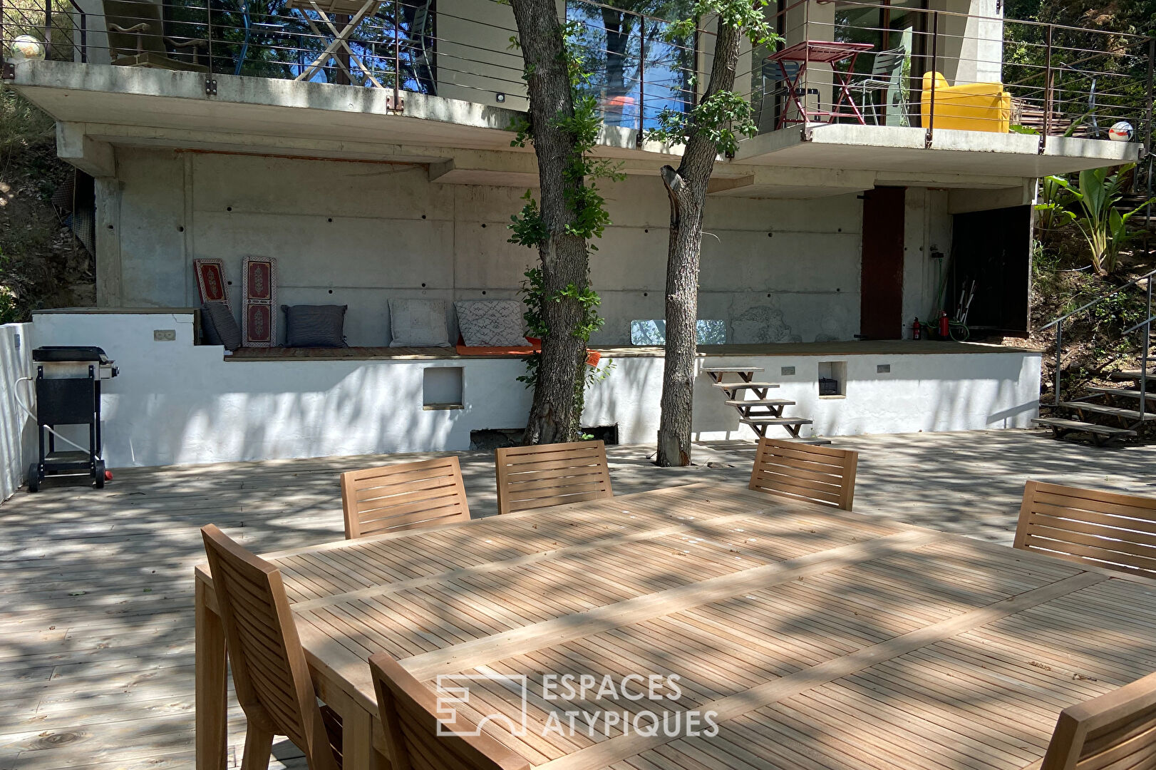 Maison brutaliste avec terrasse en bois au milieu de la forêt