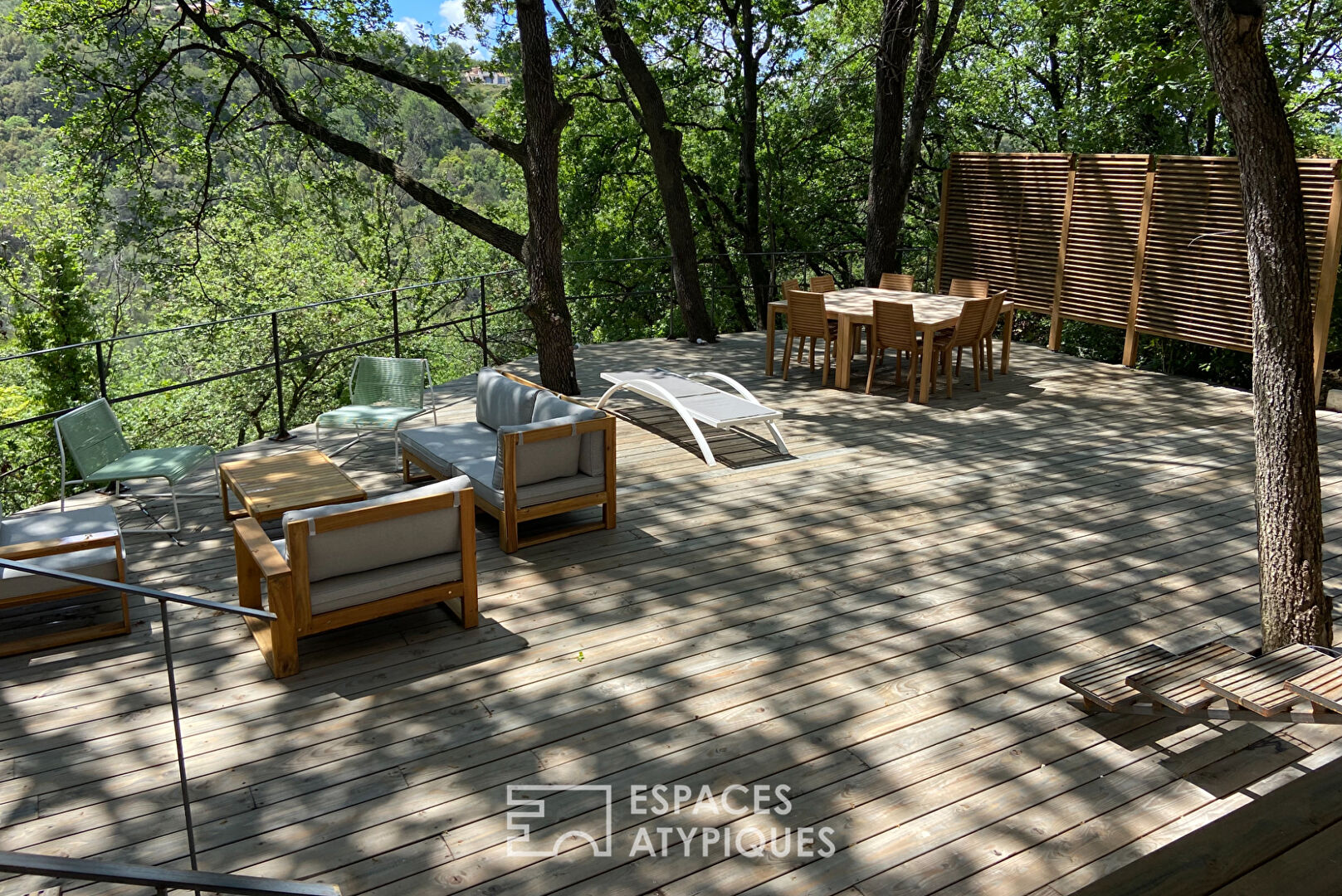 Maison brutaliste avec terrasse en bois au milieu de la forêt