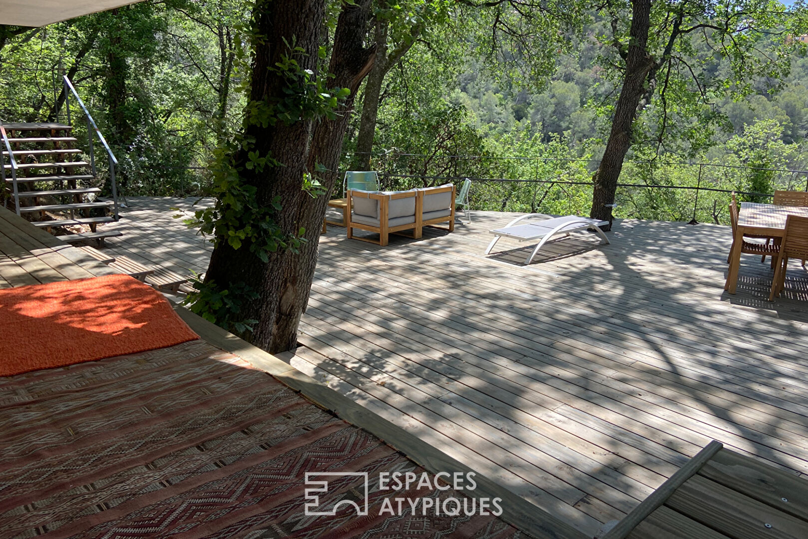 Maison brutaliste avec terrasse en bois au milieu de la forêt