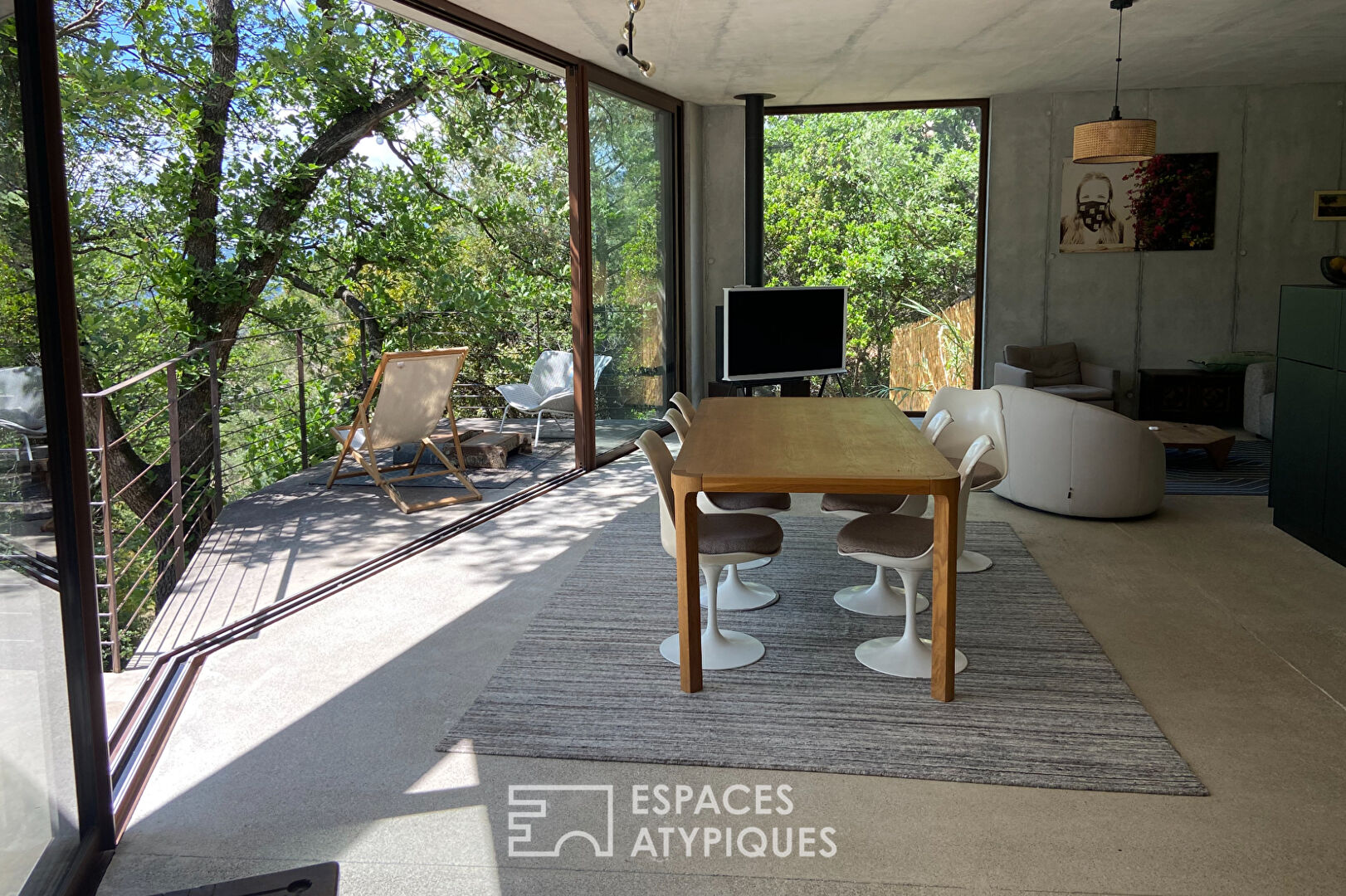 Maison brutaliste avec terrasse en bois au milieu de la forêt