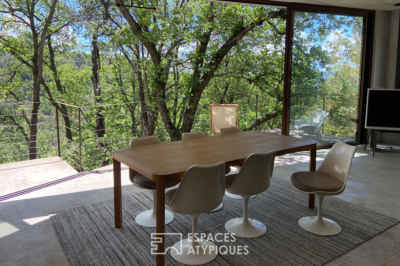 Maison brutaliste avec terrasse en bois au milieu de la forêt