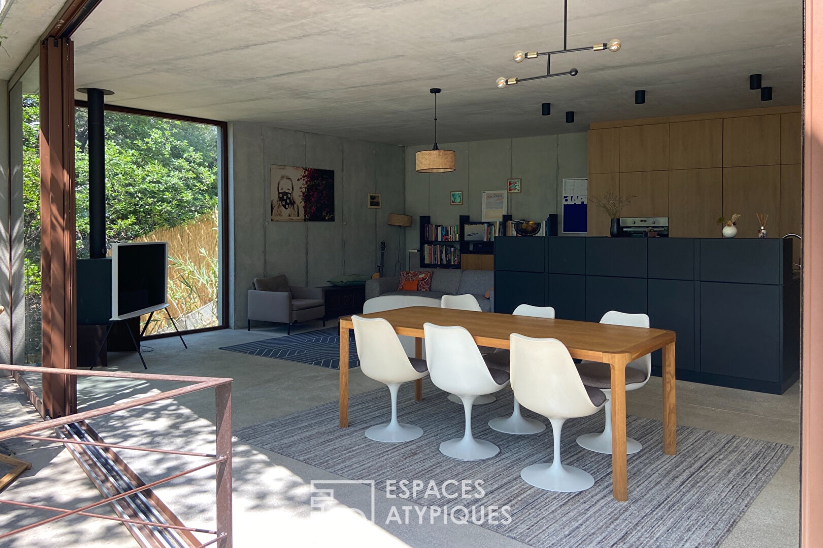 Maison brutaliste avec terrasse en bois au milieu de la forêt