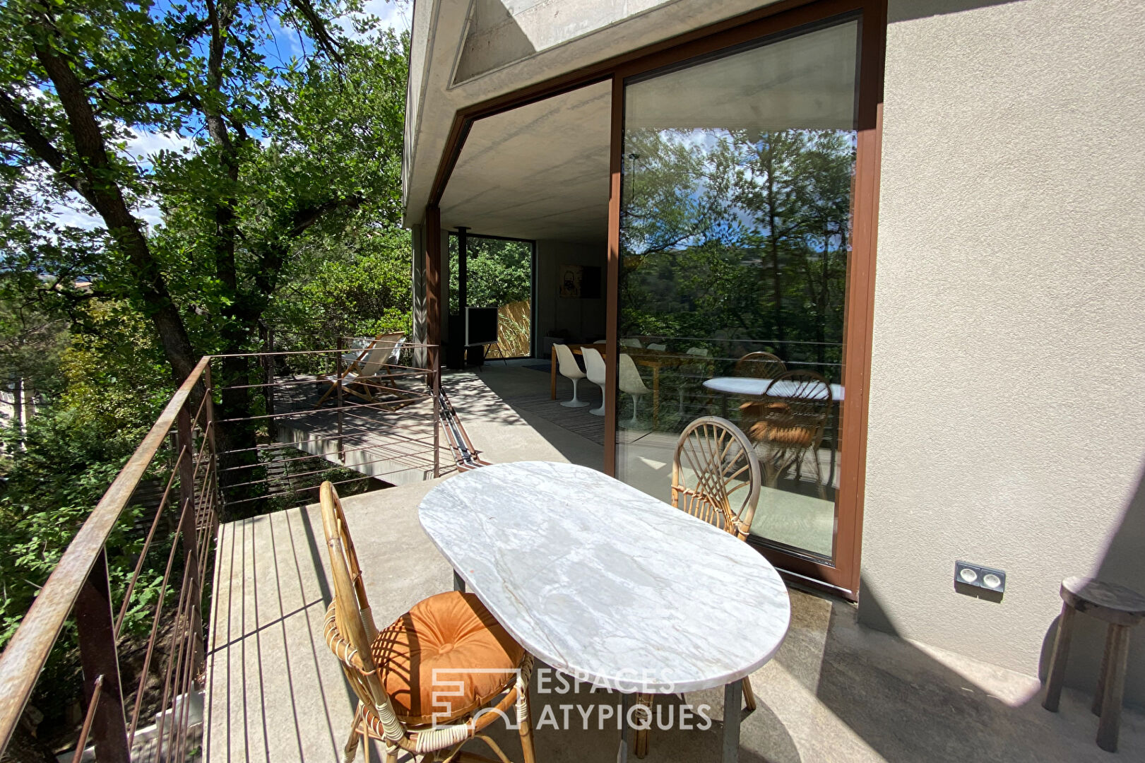 Maison brutaliste avec terrasse en bois au milieu de la forêt