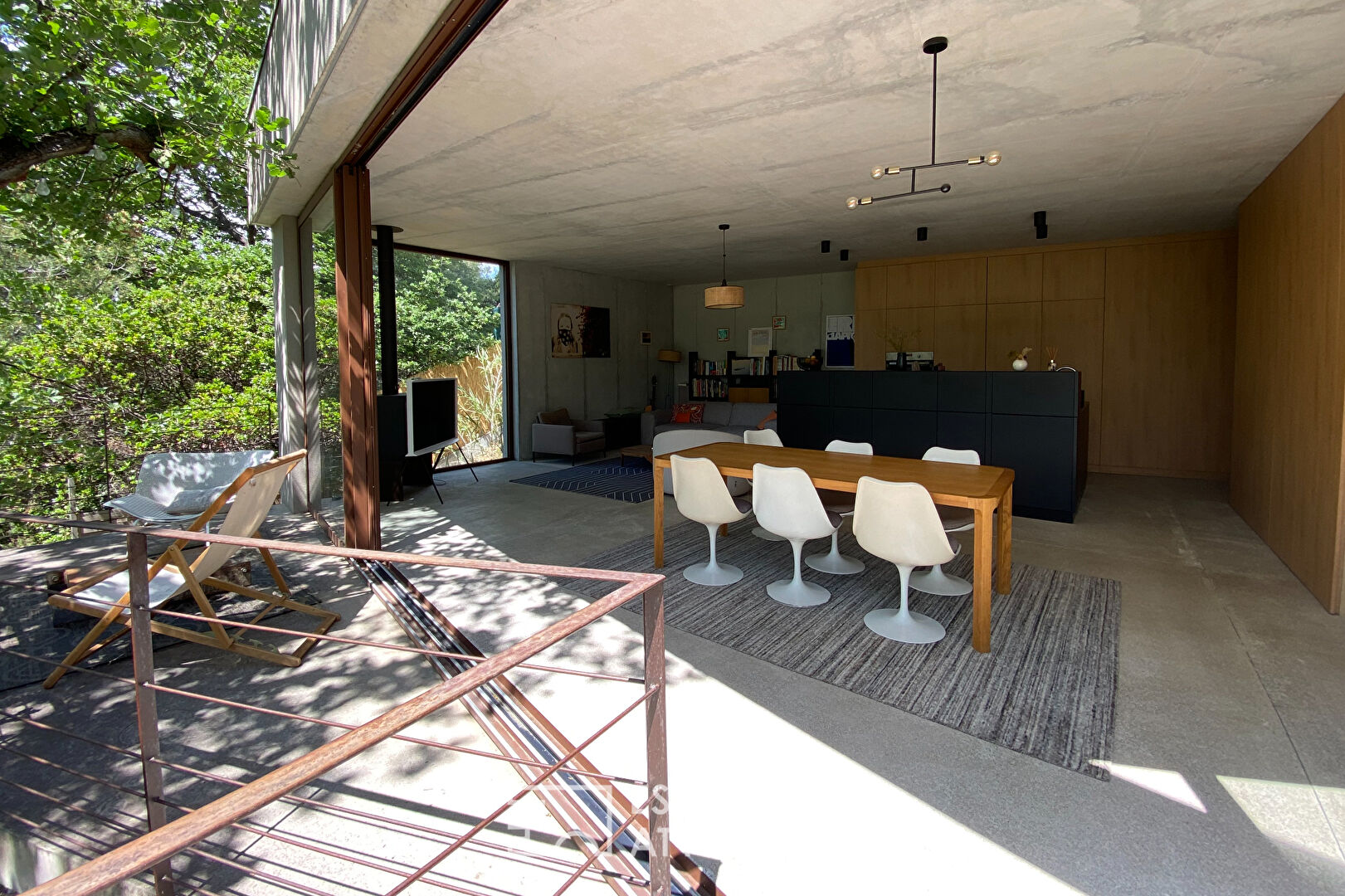 Maison brutaliste avec terrasse en bois au milieu de la forêt