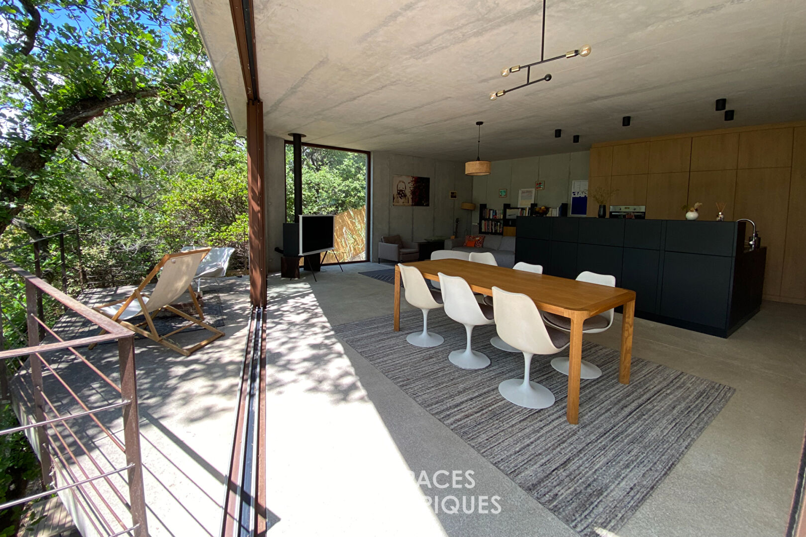 Maison brutaliste avec terrasse en bois au milieu de la forêt