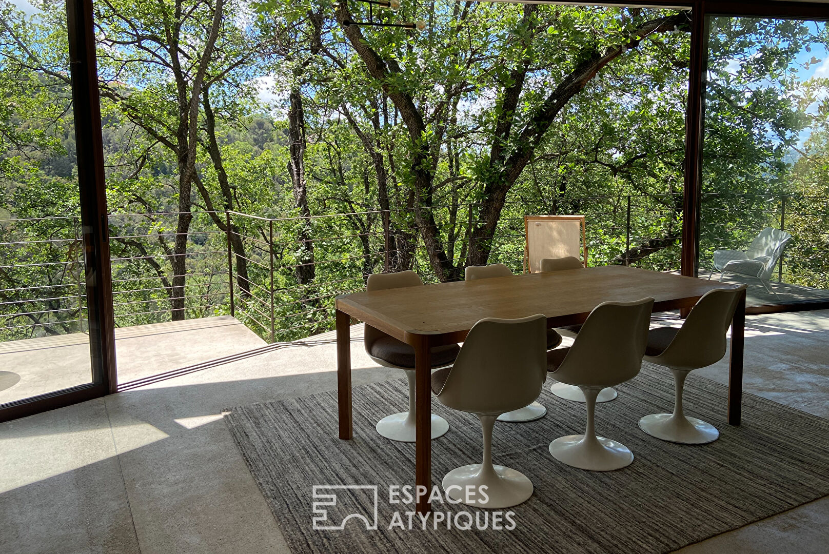 Maison brutaliste avec terrasse en bois au milieu de la forêt