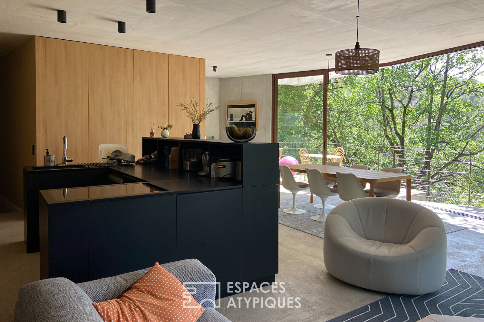 Maison brutaliste avec terrasse en bois au milieu de la forêt