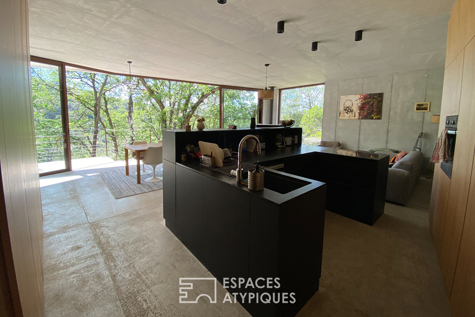 Maison brutaliste avec terrasse en bois au milieu de la forêt