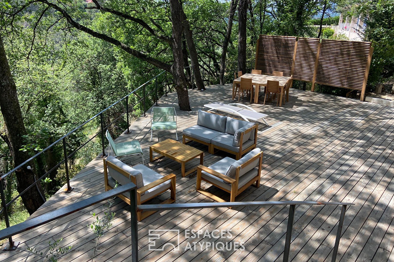 Maison brutaliste avec terrasse en bois au milieu de la forêt