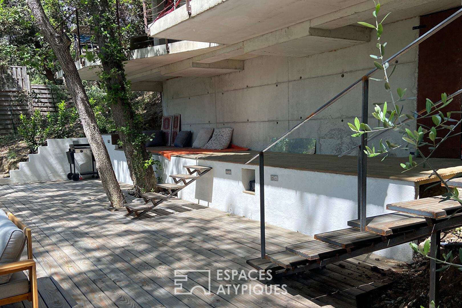 Maison brutaliste avec terrasse en bois au milieu de la forêt