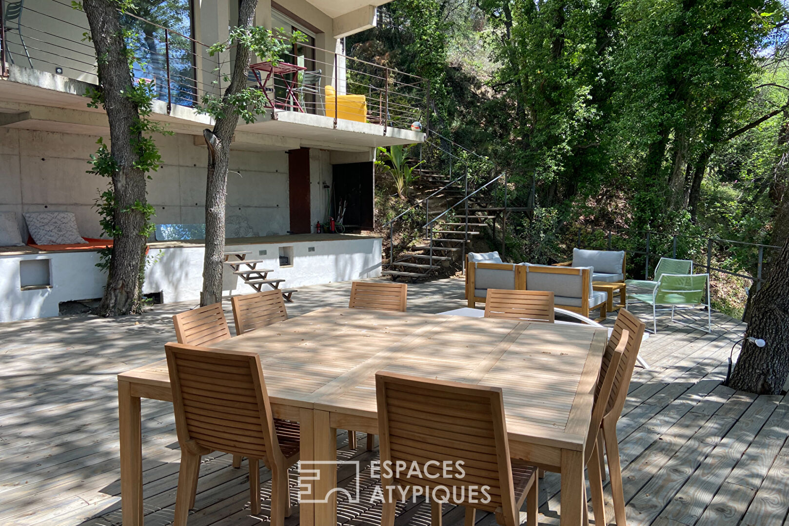 Maison brutaliste avec terrasse en bois au milieu de la forêt