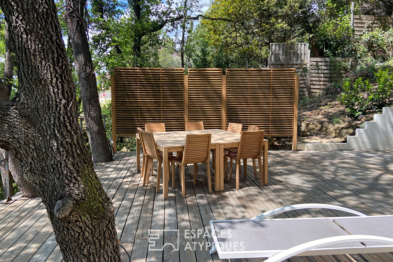 Maison brutaliste avec terrasse en bois au milieu de la forêt